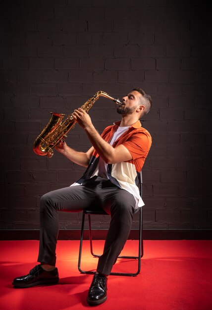 Hombre tocando el saxofón sentado en una silla