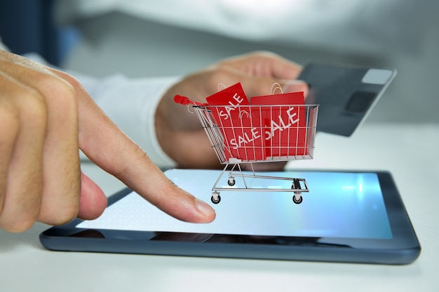 Foto gratuita hombre tocando una tablet con un carrito de la compra