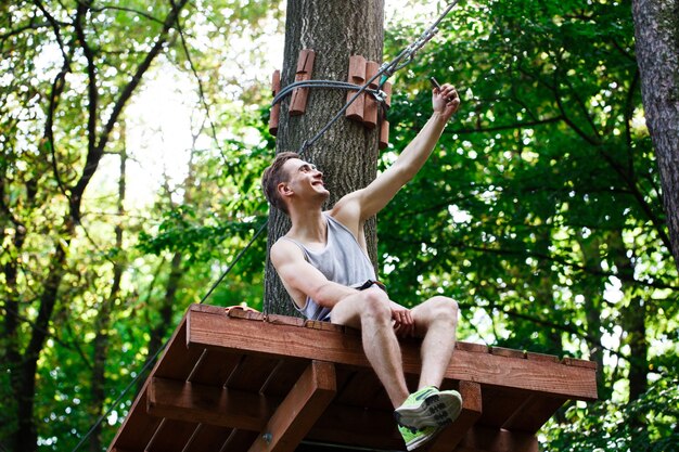 El hombre toma selfie sentado en el árbol