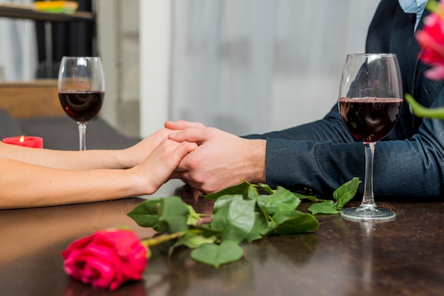 Foto gratuita hombre tomados de la mano con la mujer en la mesa con gafas y floración