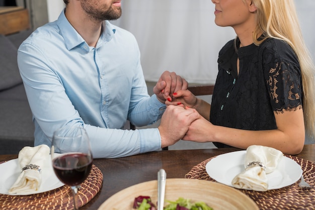 Foto gratuita hombre tomados de la mano con una mujer rubia en la mesa