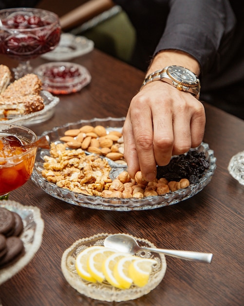 Hombre tomando avellanas del plato de nueces