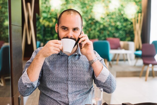 Hombre tomando café y hablando por teléfono