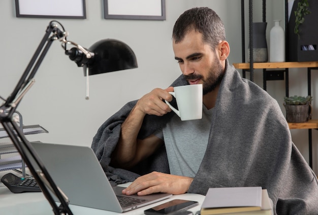 Hombre tomando café mientras trabaja desde casa