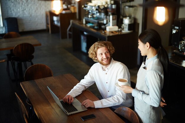 Hombre tomando café en el restaurante mientras trabajaba en la computadora portátil