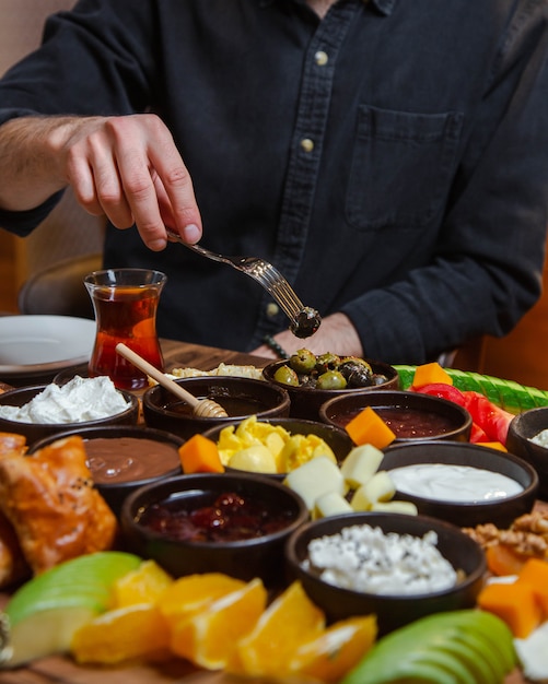 Hombre tomando comida de la mesa de desayuno totalmente donada con alimentos mixtos.