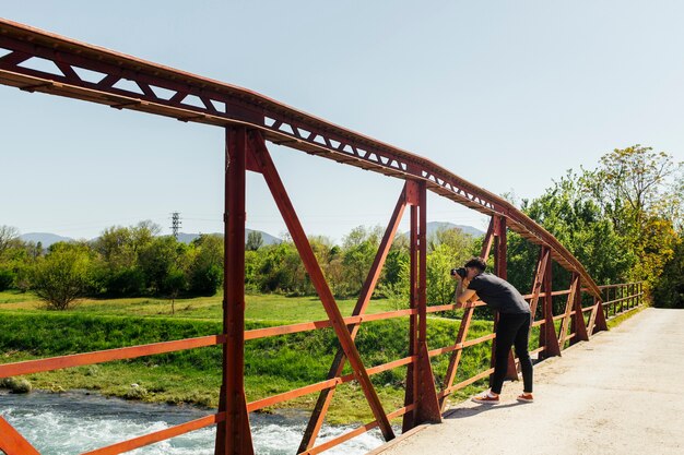 Hombre tomando foto de agua que fluye desde el puente