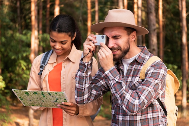 Hombre tomando fotos mientras su novia está revisando un mapa