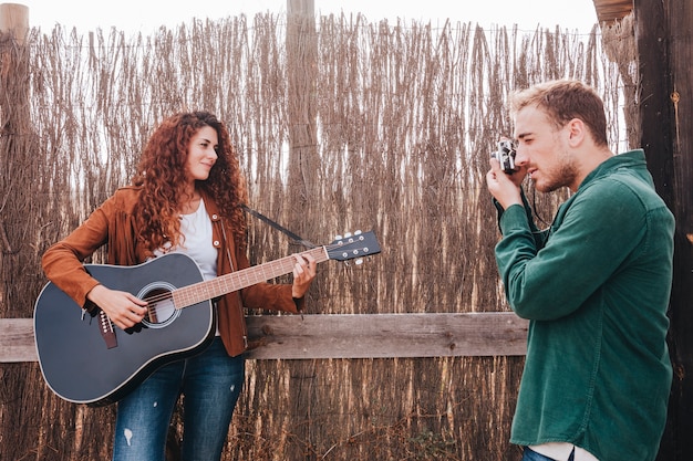 Hombre tomando fotos de mujer tocando guitarra