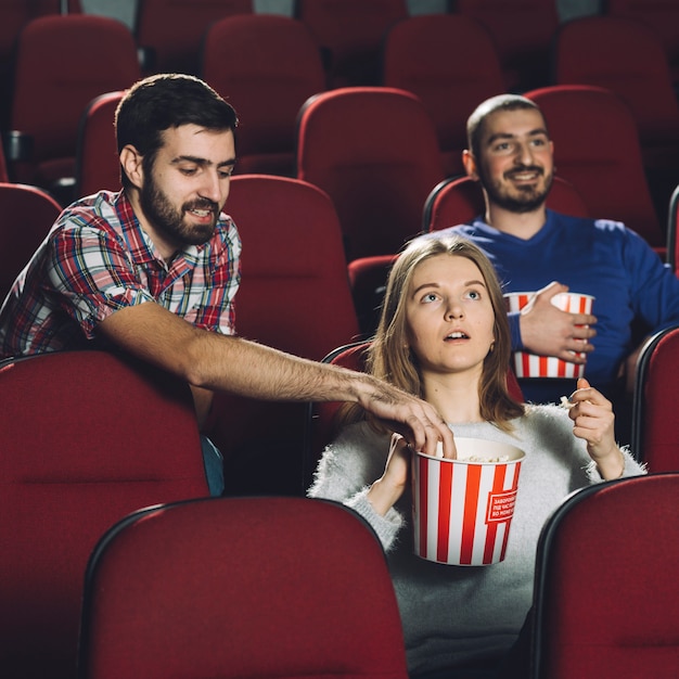 Hombre tomando palomitas de maíz de mujer durante la película