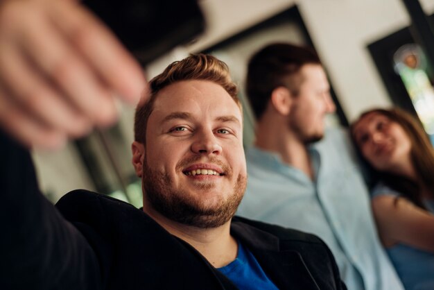 Hombre tomando selfie con amigos en el interior