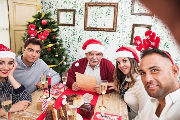 Hombre tomando selfie con familia en mesa festiva
