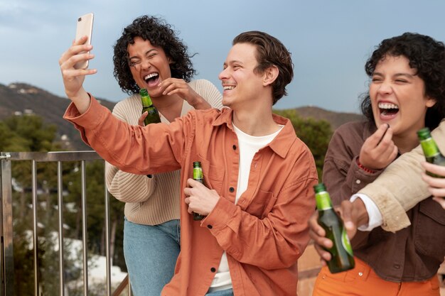 Hombre tomando selfie con sus amigos durante una fiesta al aire libre