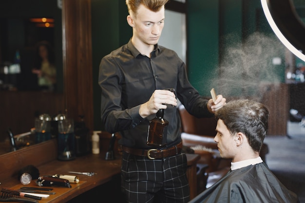 El hombre trabaja con el cabello. Peluquería con cliente.