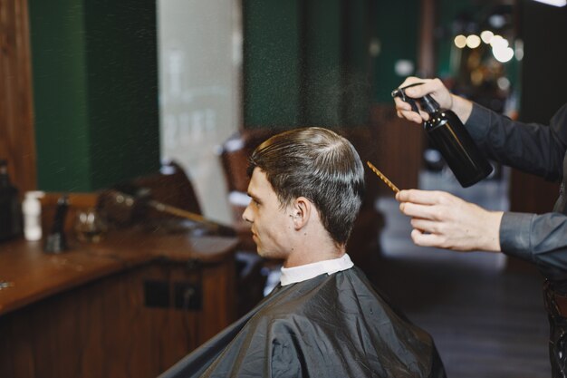 El hombre trabaja con el cabello. Peluquería con cliente.