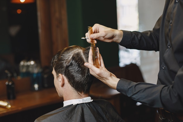 El hombre trabaja con el cabello. Peluquería con cliente.