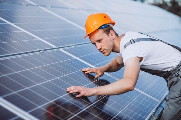 Foto gratuita hombre trabajador en el campo junto a los paneles solares.