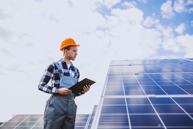 Foto gratuita hombre trabajador en el campo junto a los paneles solares.