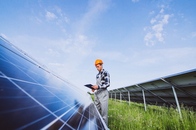 Foto gratuita hombre trabajador en el campo junto a los paneles solares.