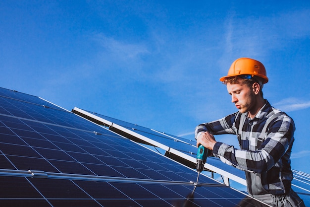 Foto gratuita hombre trabajador en el campo junto a los paneles solares.