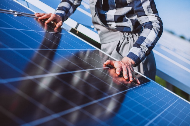 Foto gratuita hombre trabajador en el campo junto a los paneles solares.