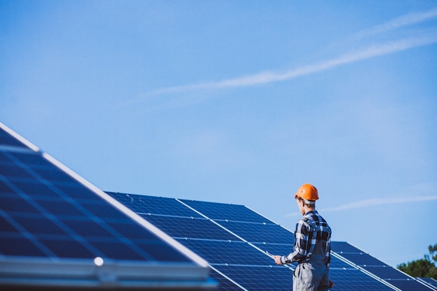 Hombre trabajador en el campo junto a los paneles solares.