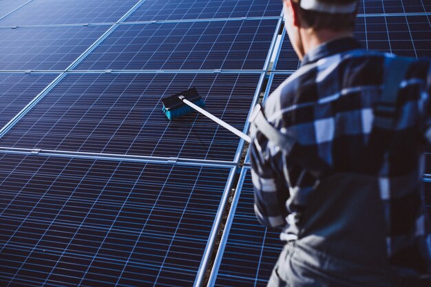 Hombre trabajador en el campo junto a los paneles solares.