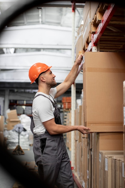 Hombre trabajando en almacén logístico plano medio