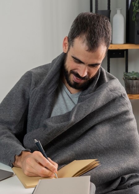 Hombre trabajando desde casa y escribiendo en el cuaderno