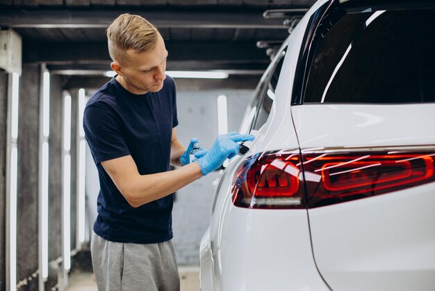 Hombre trabajando en el coche que detalla y recubre el coche