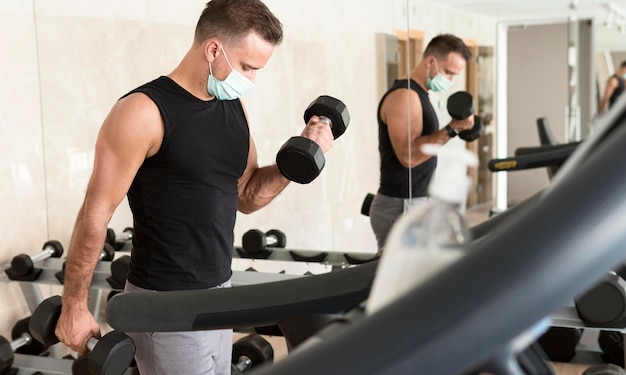 Foto gratuita hombre trabajando en el gimnasio con máscara médica