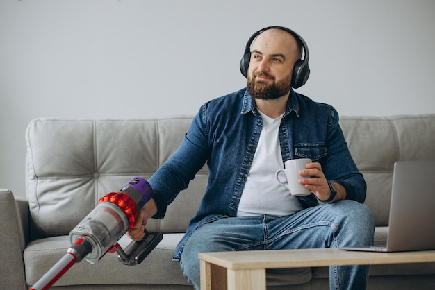 Foto gratuita hombre trabajando en una laptop y aspirando la casa