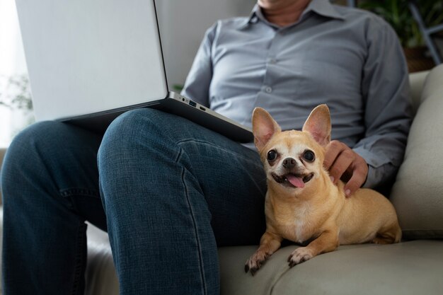 Hombre trabajando en una laptop en casa junto a su perro