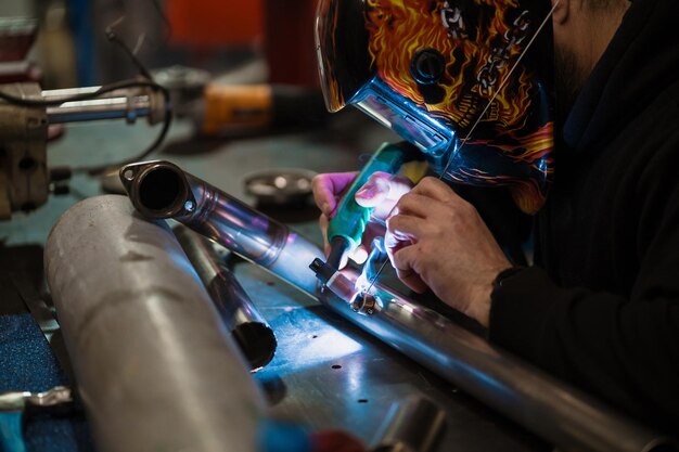 Hombre trabajando con máquina de soldadura de argón en un garaje