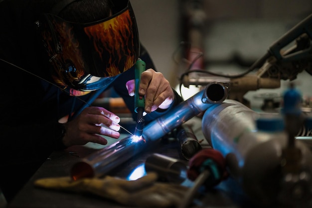 Hombre trabajando con máquina de soldadura de argón en un garaje