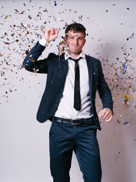 Hombre en traje bailando bajo lentejuelas brillantes