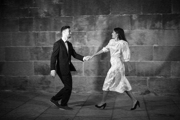 Hombre en traje bailando con mujer en calle de noche