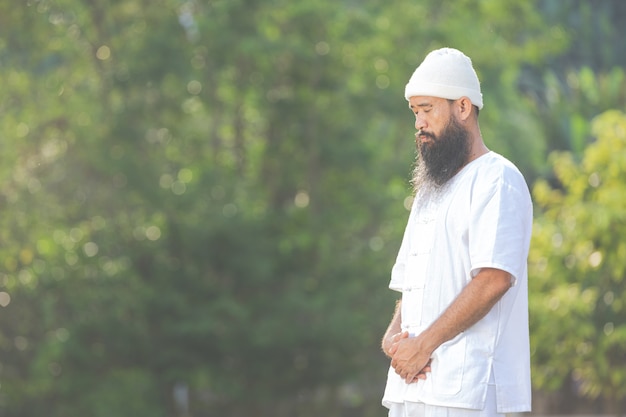 Hombre en traje blanco meditando en la naturaleza