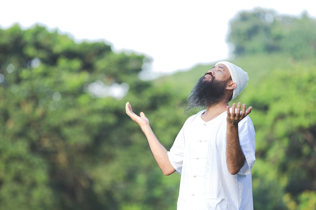 Hombre en traje blanco meditando en la naturaleza