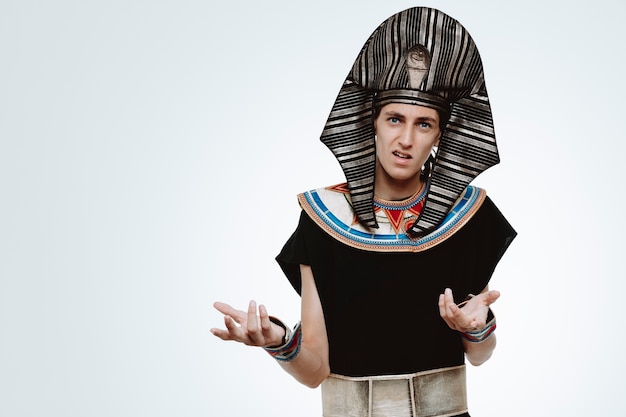 Hombre en traje egipcio antiguo confundido y disgustado levantando los brazos con indignación en blanco