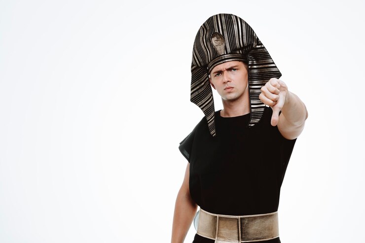Foto gratuito hombre en traje egipcio antiguo con rostro serio mostrando el pulgar hacia abajo en blanco