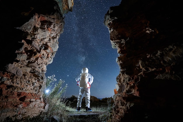 El hombre en traje espacial está mirando en el cielo estrellado