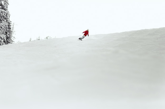 El hombre en traje de esquí rojo ejecuta una vuelta en el talón