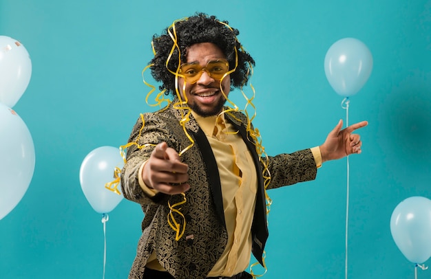 Hombre de traje y gafas de sol en la fiesta con globos apuntando