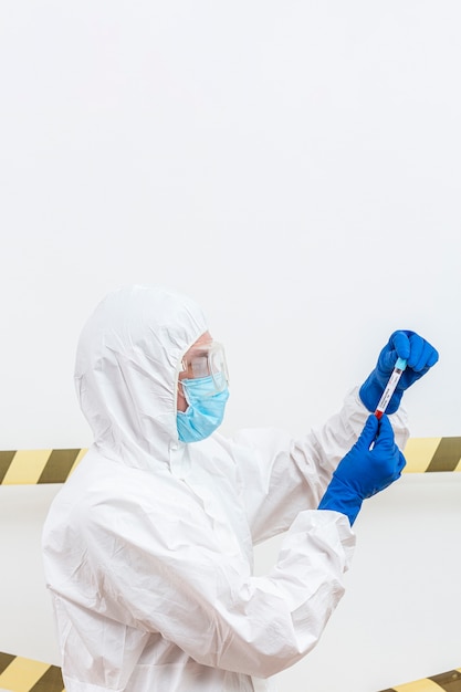 Foto gratuita hombre en traje de materiales peligrosos con muestra de sangre