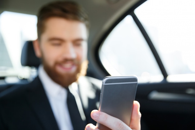 Hombre en traje mirando el teléfono móvil en su mano