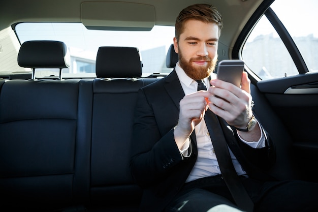 Foto gratuita hombre en traje mirando el teléfono móvil en su mano