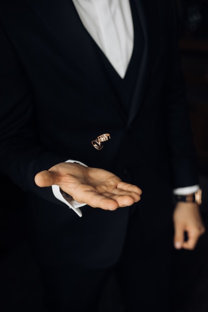 Foto gratuita el hombre del traje negro está lanzando dos anillos de boda