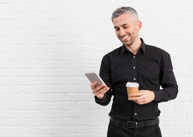 Foto gratuita hombre de traje negro con teléfono y café