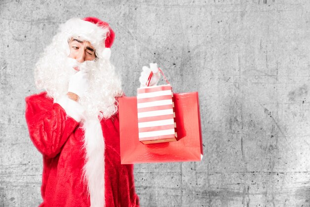 Hombre con traje de papá noel sujetando bolsas de la compra